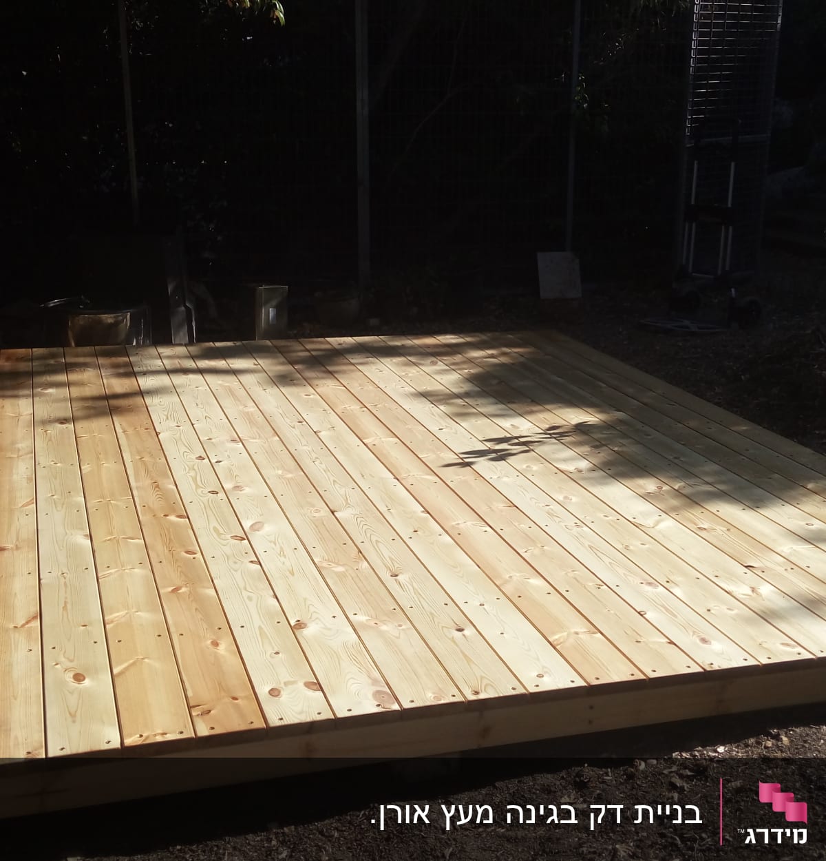 משטח עץ בנוי בגינה עם צללים מסביב